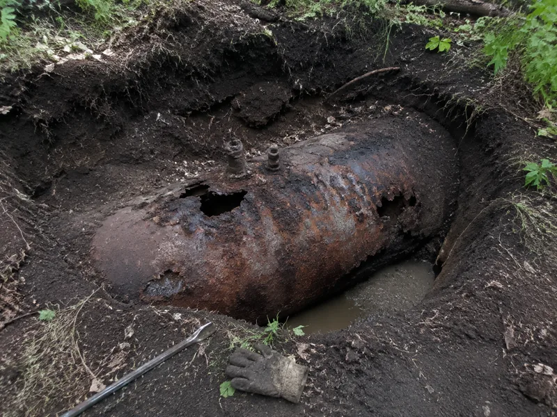 Abandoned oil tank removal New Bedford, rusted-through buried tank uncovered in an overgrown backyard