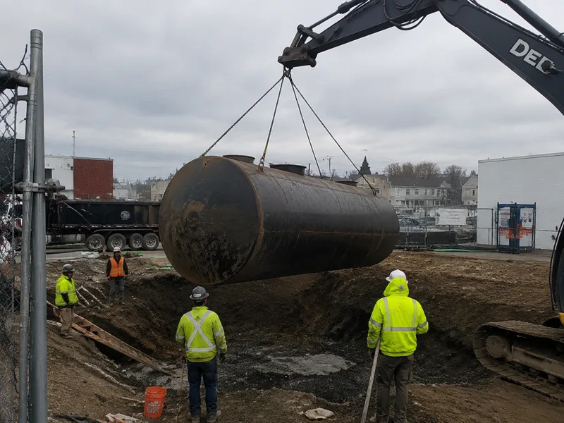 Commercial tank removal New Bedford, large steel underground storage tank hoisted from an excavation