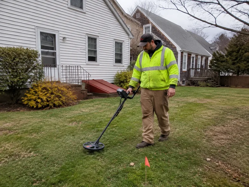 Oil tank sweep New Bedford, technician scanning a yard with a metal detector for a buried tank